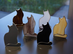 Suncatcher Cat is made of colored glass in stained glass Tiffany technique, hanging or standing on table, shelf sitters . There are color options for cats - black, white, gray, brown mottled, cocoa color, and light amber